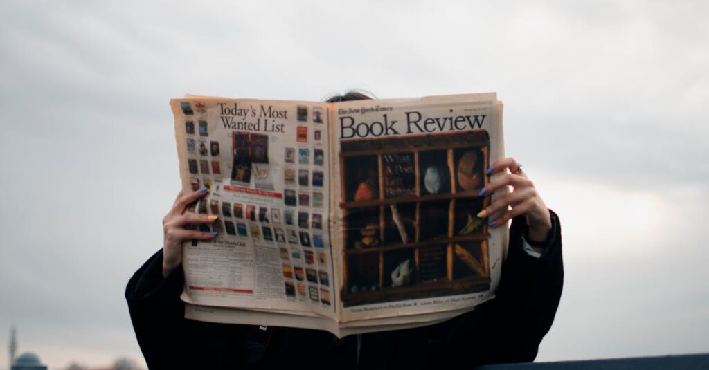 Individual holding a book review newspaper with colorful nails against a cloudy sky backdrop.