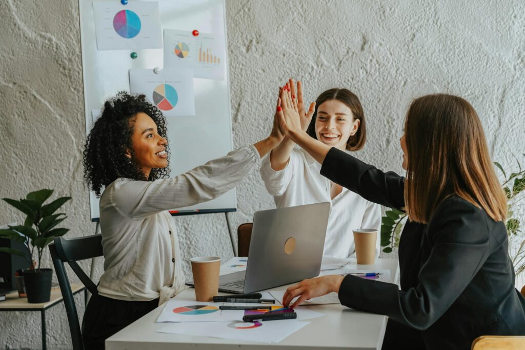 Three businesswomen in office having a high-five during a successful meeting.
